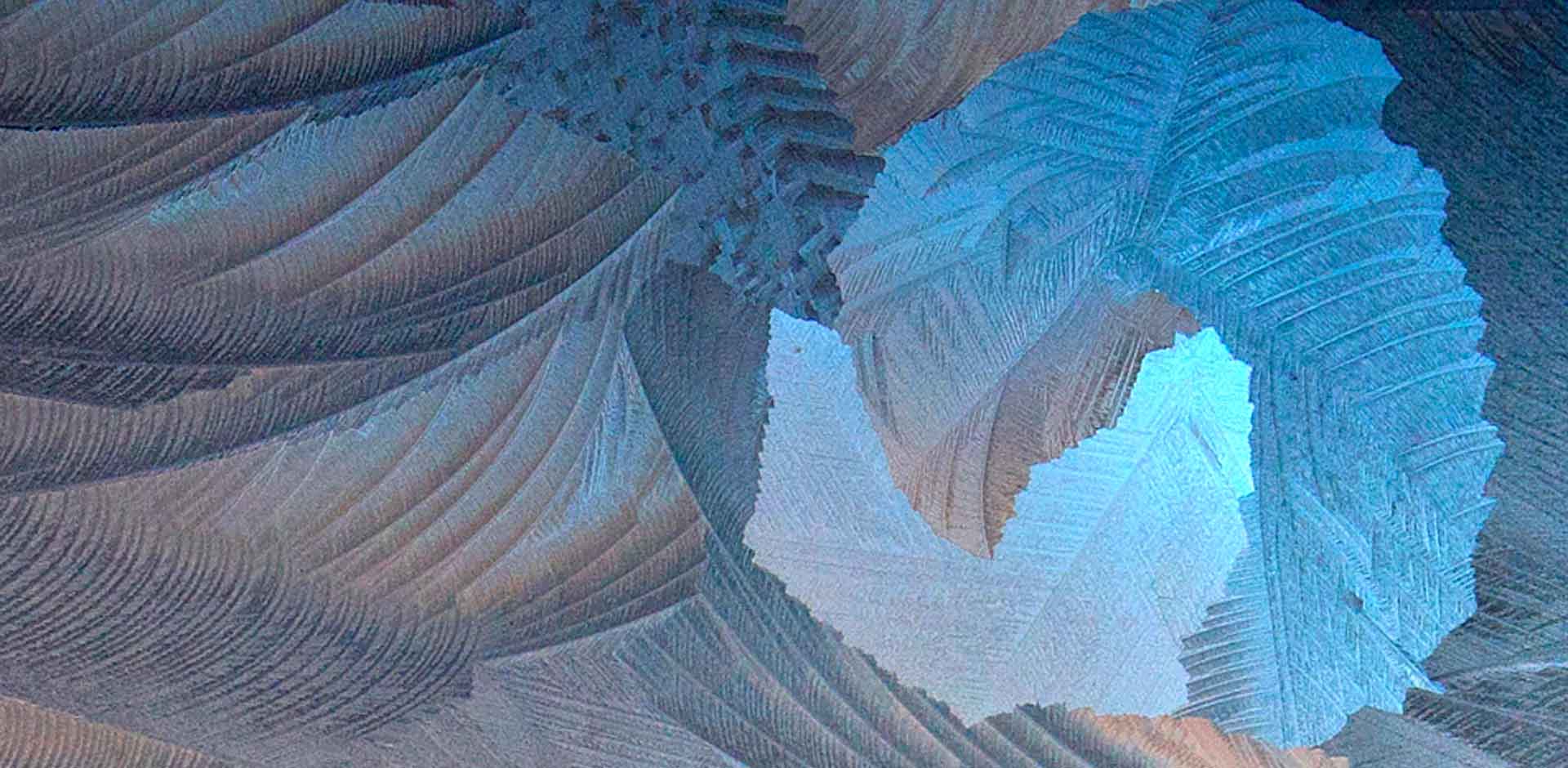 窓に張った氷の結晶が青く輝く抽象的な模様